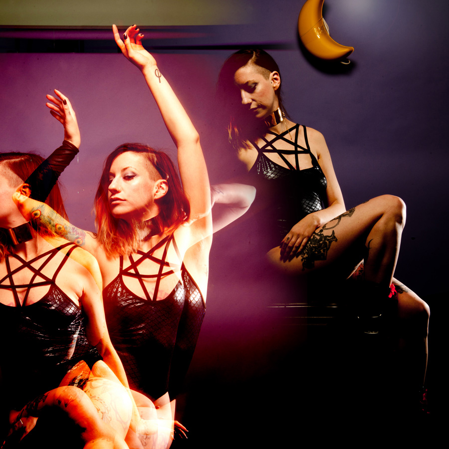 Blended photo of Madison Rexx in the purple room: one image is a triple exposure of her arms raised gracefully in the air and also turning away. This has been digitally blended with a different photo in which she is seated and looking downward with an expression of repose.